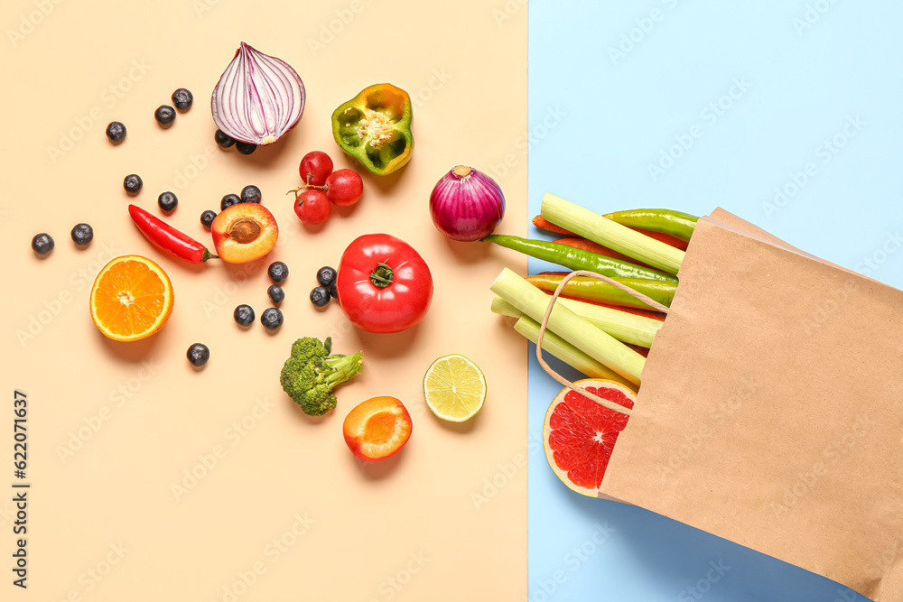 Paper bag with different fresh fruits and vegetables on colorful background