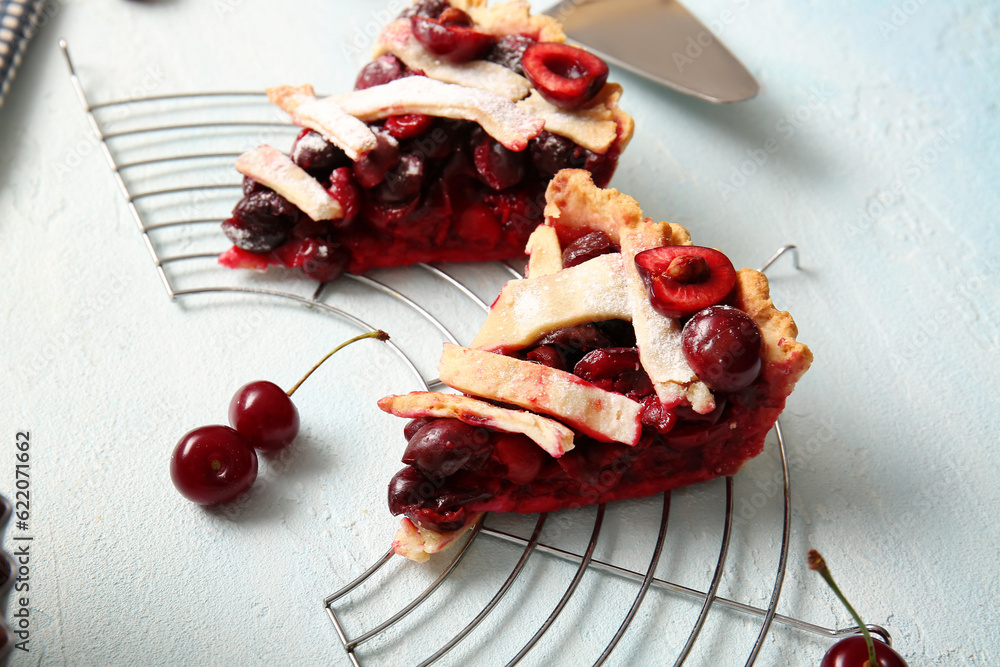 Stand with pieces of tasty cherry pie on blue background