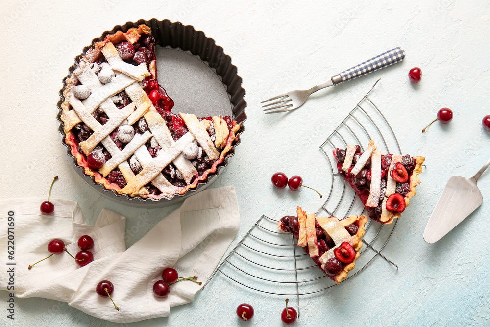 Baking dish with tasty cherry pie and stand of pieces on blue background