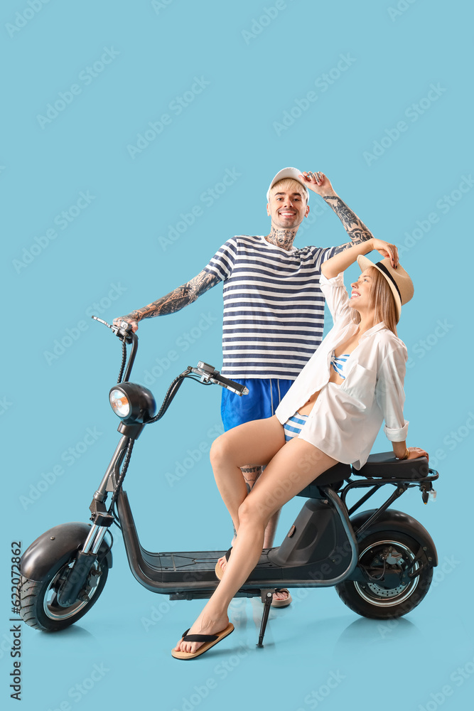 Young couple with electric bike on blue background