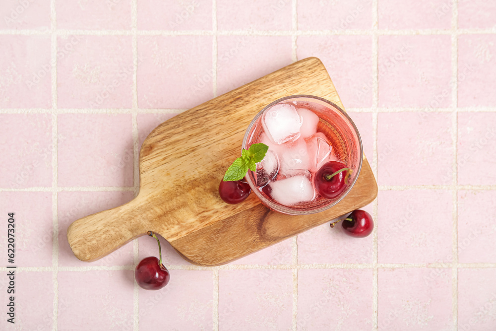 Wooden board with glass of tasty cherry lemonade and mint on pink tile table