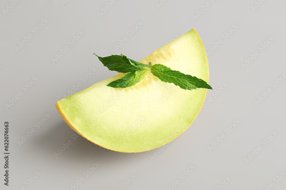 Piece of sweet melon and mint on grey background