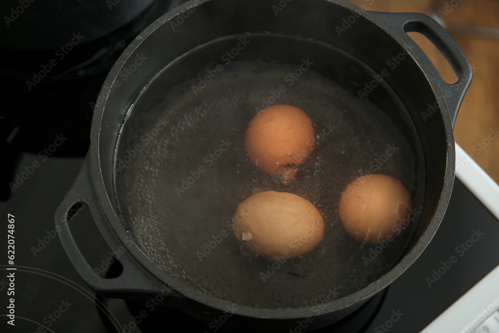 Chicken eggs boiling in cooking pot, closeup