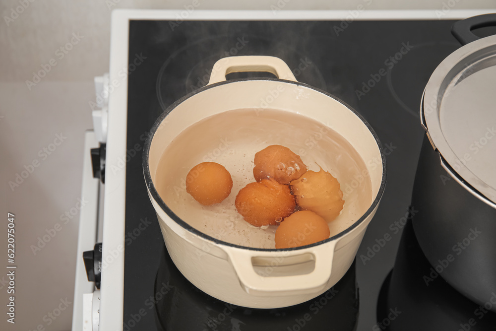 Chicken eggs boiling in cooking pot on stove