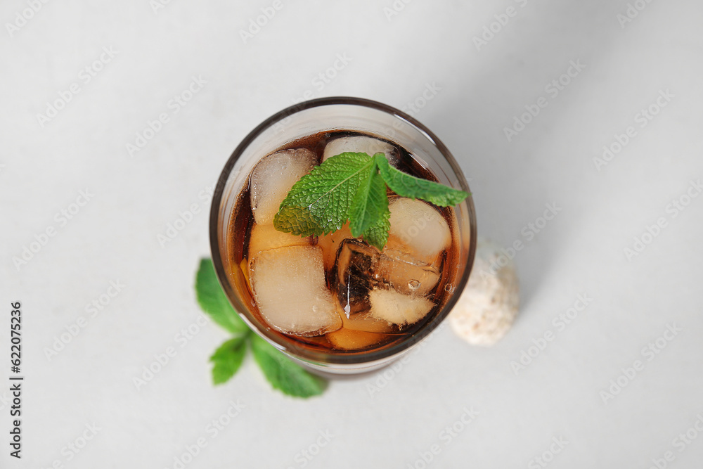 Glass of cold Cuba Libre cocktail and seashell on white background