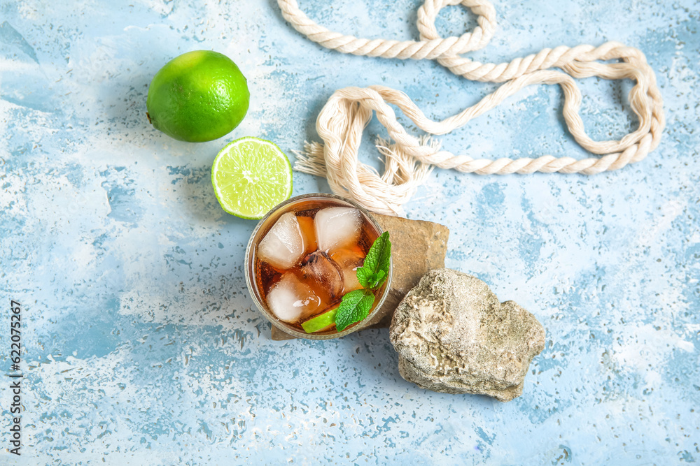 Stones with glass of cold Cuba Libre cocktail on blue background