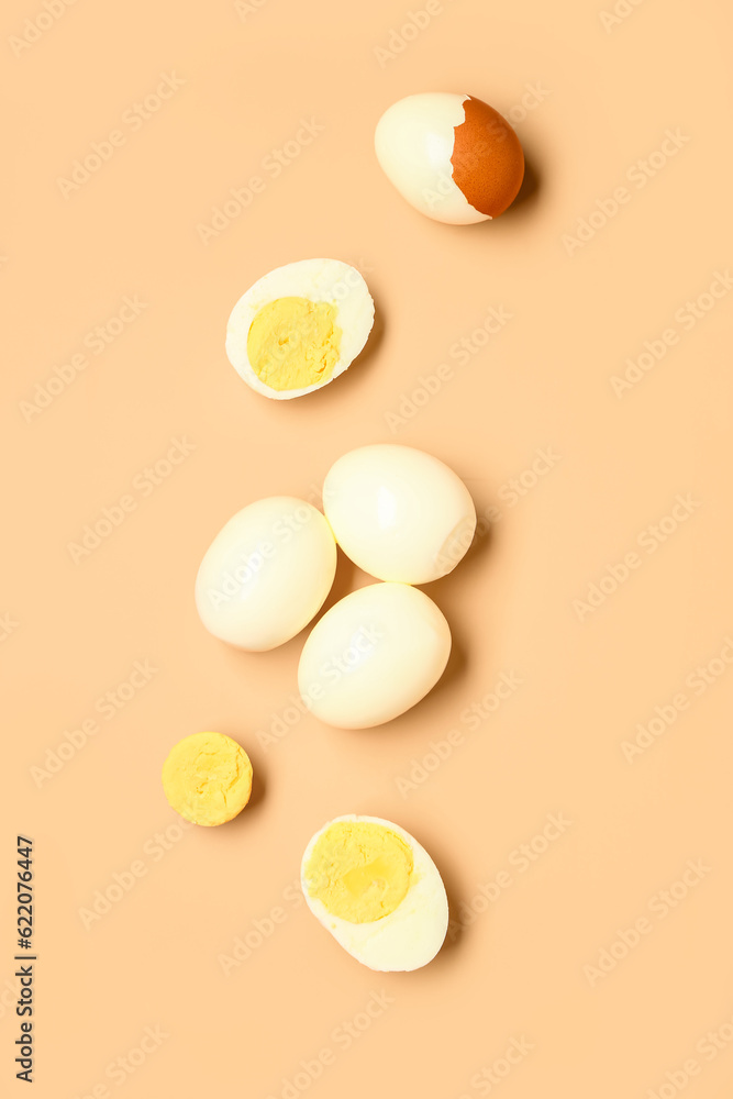 Tasty boiled eggs with halves on orange background