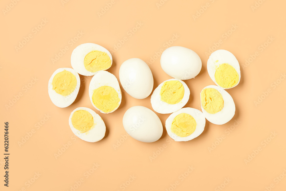 Tasty boiled eggs with halves on orange background