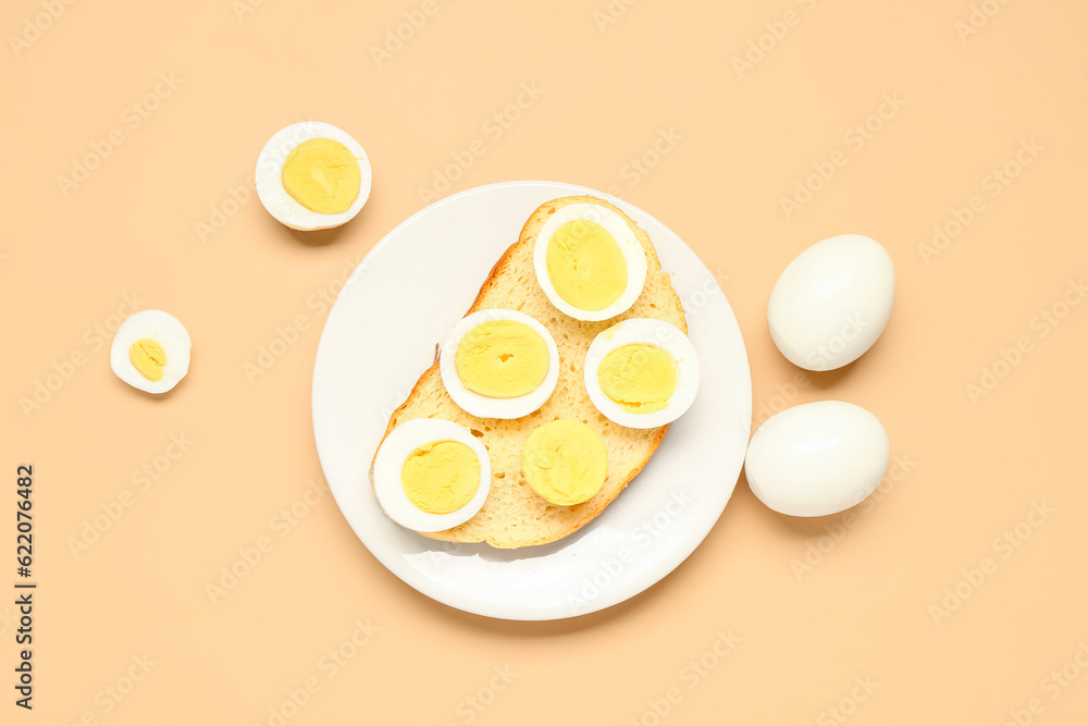 Plate of toast with boiled eggs on orange background