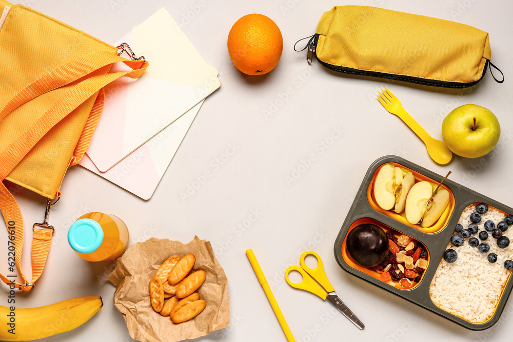 Backpack, stationery and lunchbox with tasty food on grey background