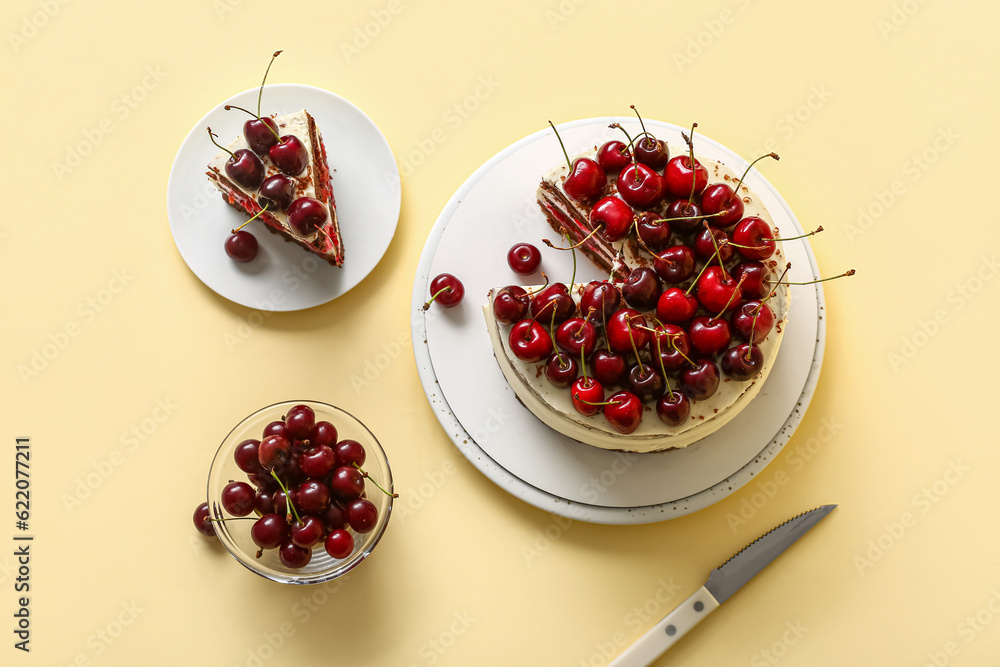 Plates with tasty cherry cake on yellow background