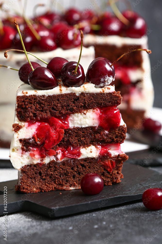 Board with piece of tasty cherry cake on table