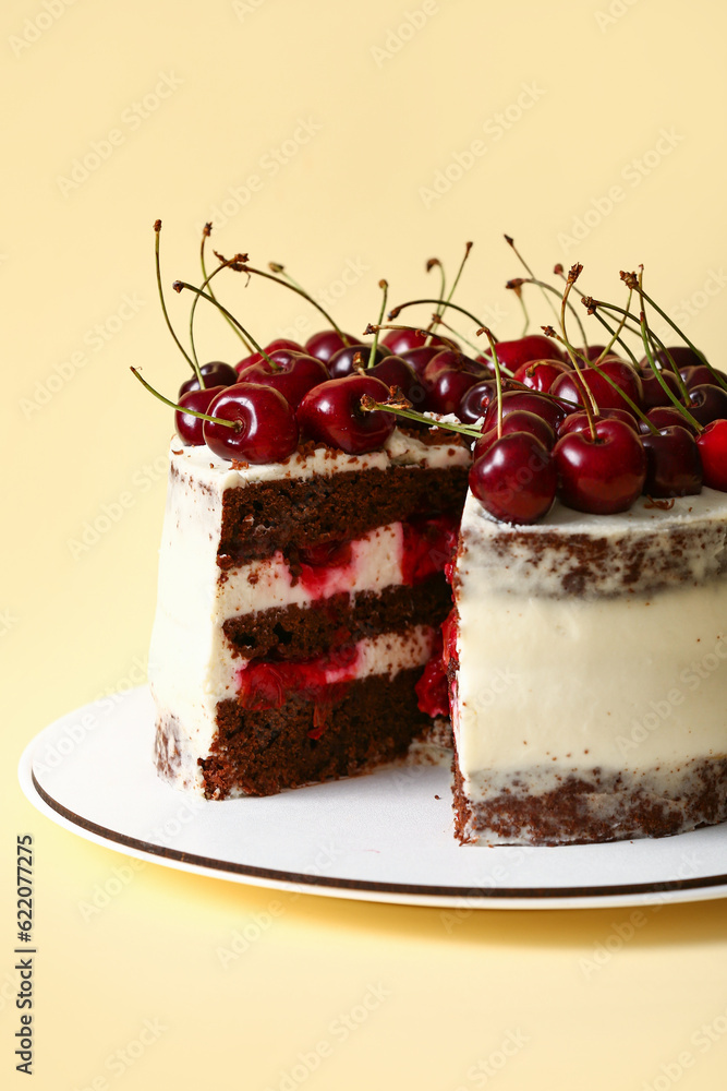 Plate with tasty cherry cake on yellow background