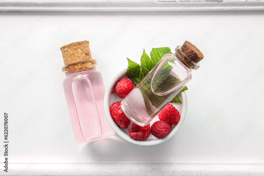 Bottles of cosmetic raspberry oil on white table