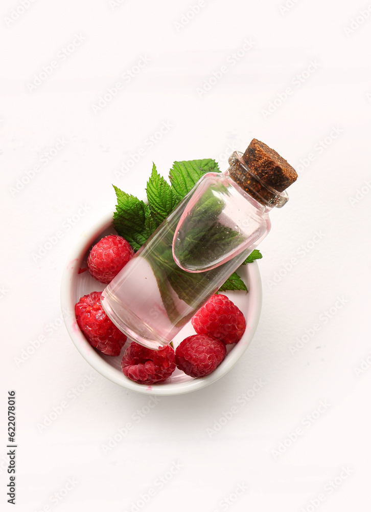 Bottle of cosmetic raspberry oil on white table