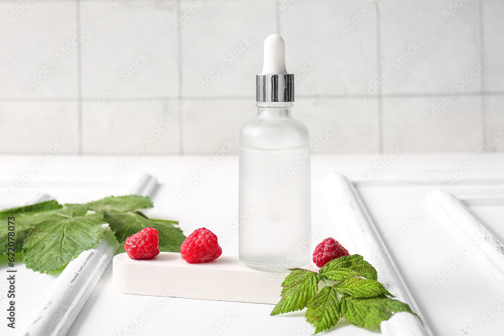 Bottle of cosmetic raspberry oil on white table