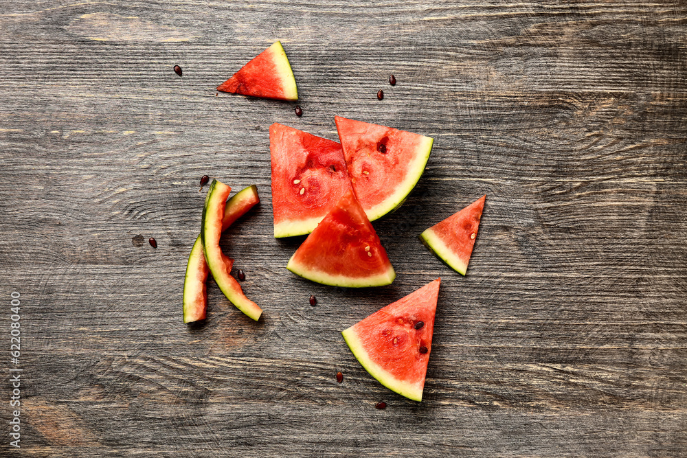 Pieces of fresh watermelon and seeds on wooden background