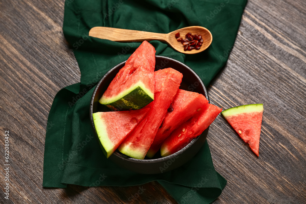 Bowl with pieces of fresh watermelon and seeds on wooden background