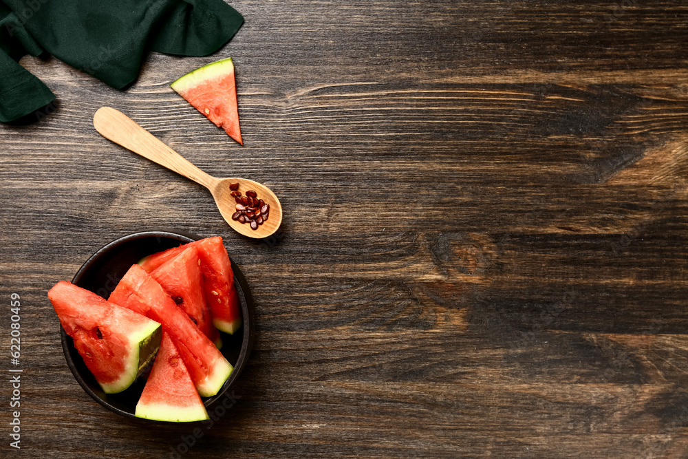 Bowl with pieces of fresh watermelon and seeds on wooden background