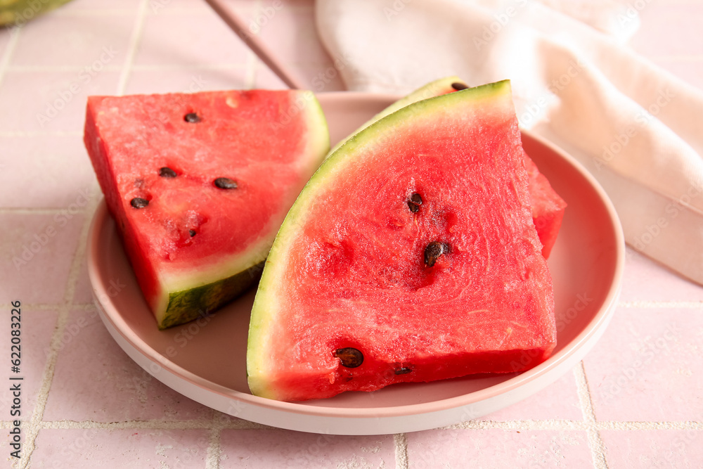 Plate with pieces of fresh watermelon on pink tile table