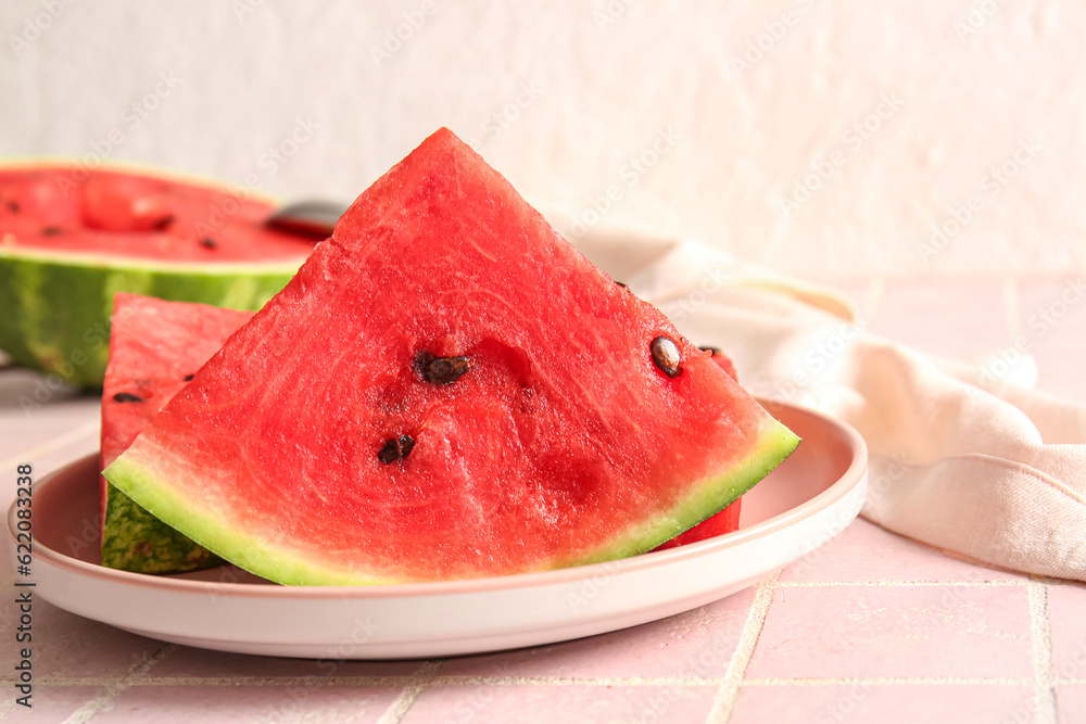 Plate with pieces of fresh watermelon on pink tile table