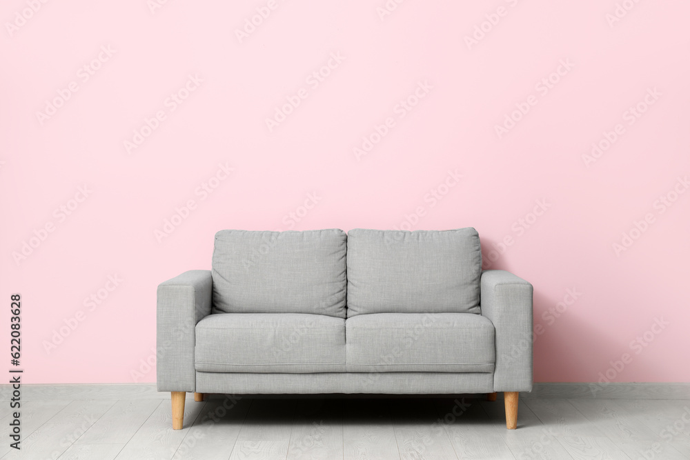 Cozy grey sofa near pink wall