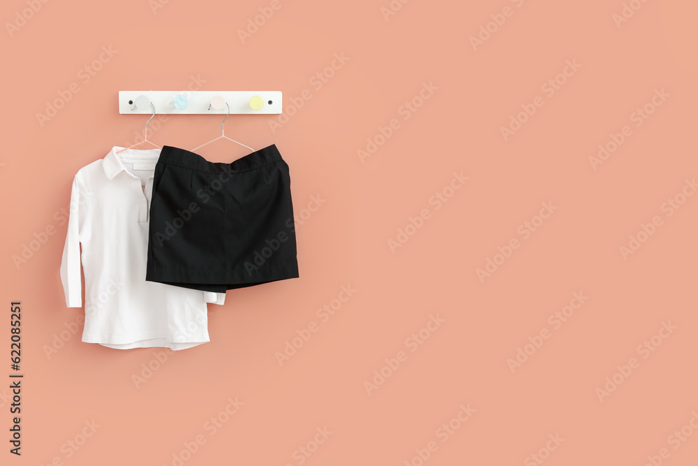 Stylish school uniform hanging on beige wall in room