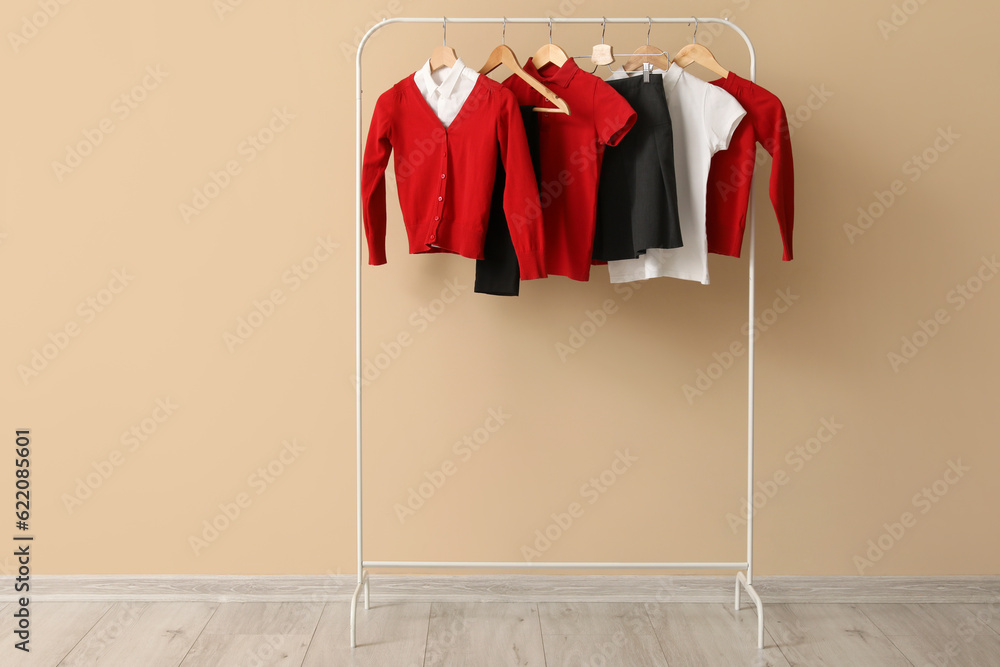 Rack with stylish school uniform against color wall