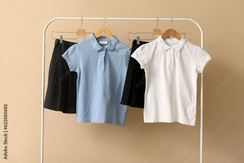 Rack with stylish school uniform on color background