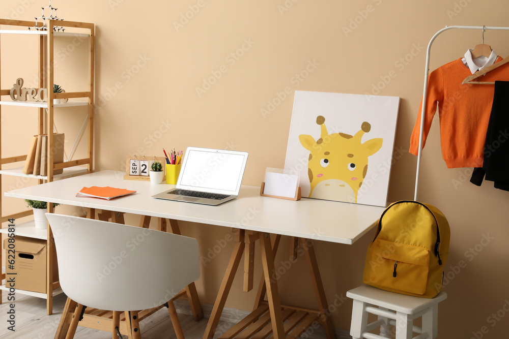 Stylish interior of childrens room with modern laptop and school uniform