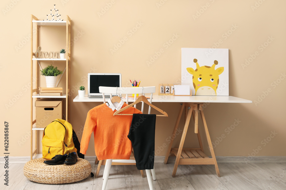 Stylish interior of childrens room with modern laptop and school uniform