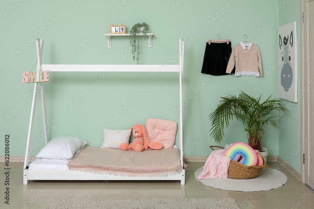 Stylish interior on childrens bedroom with school uniform and houseplant