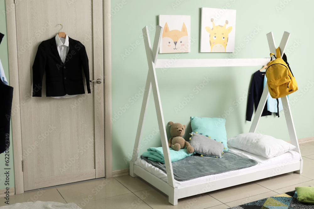 Stylish interior of childrens room with comfortable bed and school uniform