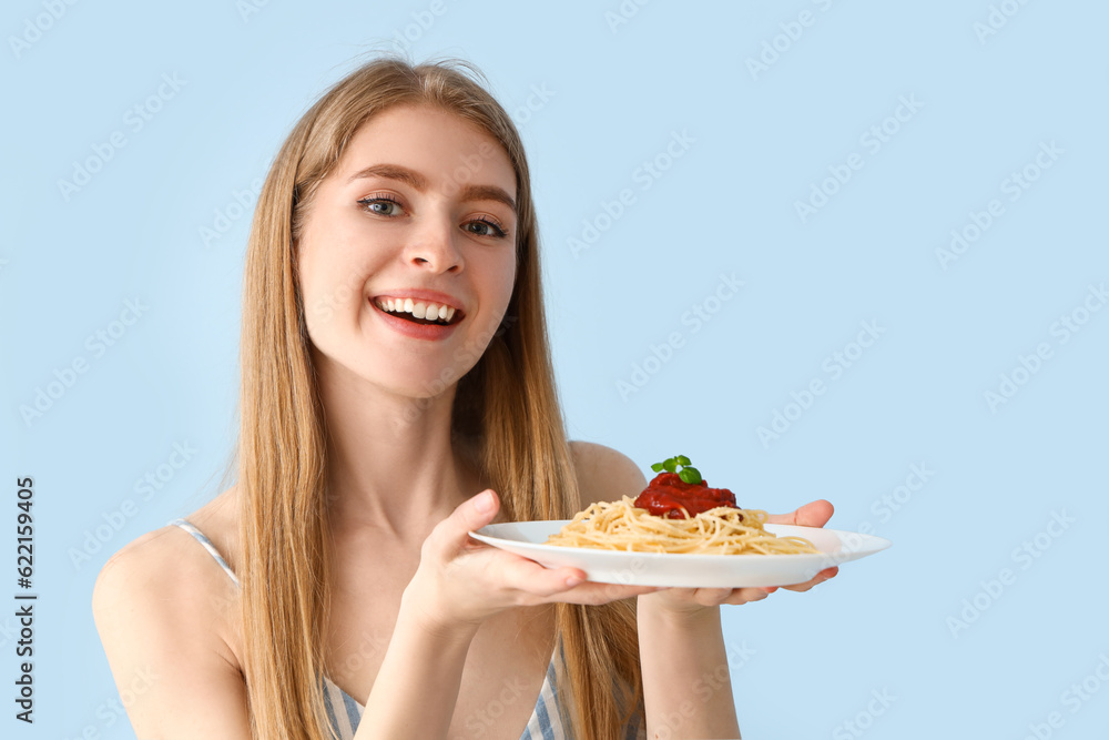 Young woman with tasty pasta on blue background, closeup