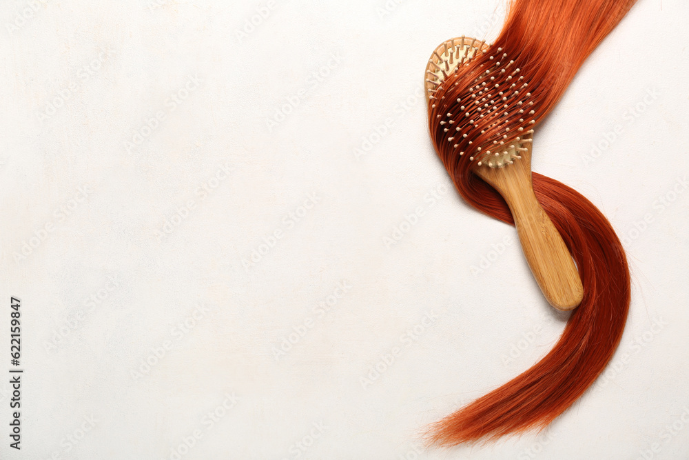 Ginger hair strand with brush on light background