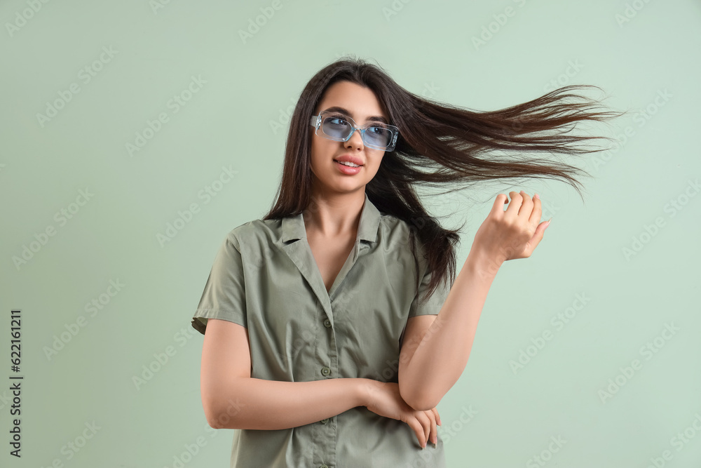 Beautiful young woman wearing stylish  sunglasses on color background