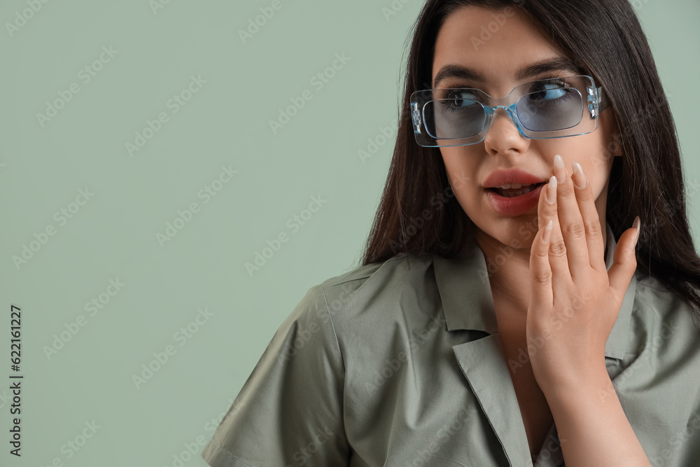 Beautiful young woman wearing stylish  sunglasses on color background