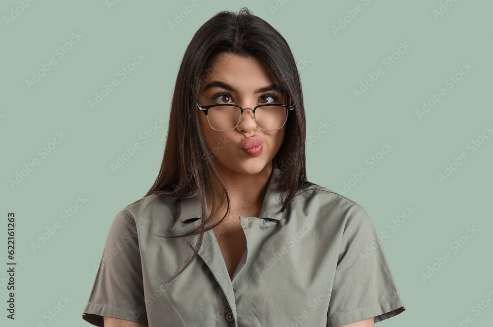 Funny young woman wearing glasses on color background