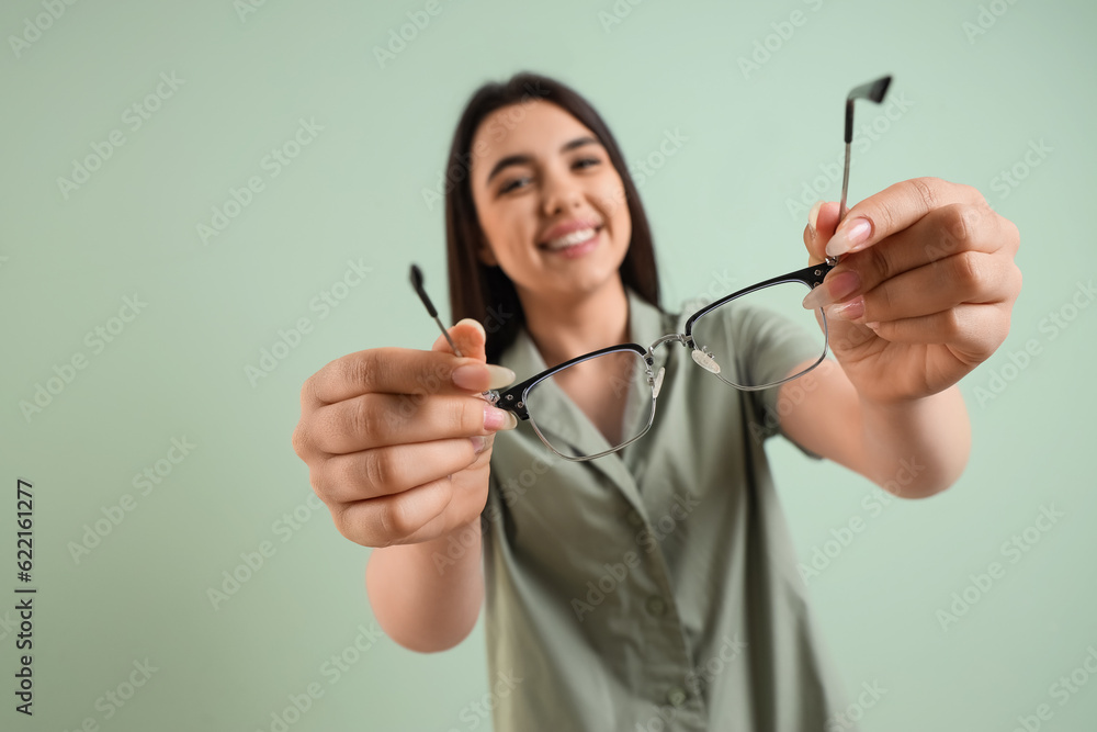 Beautiful young woman with glasses on  color background