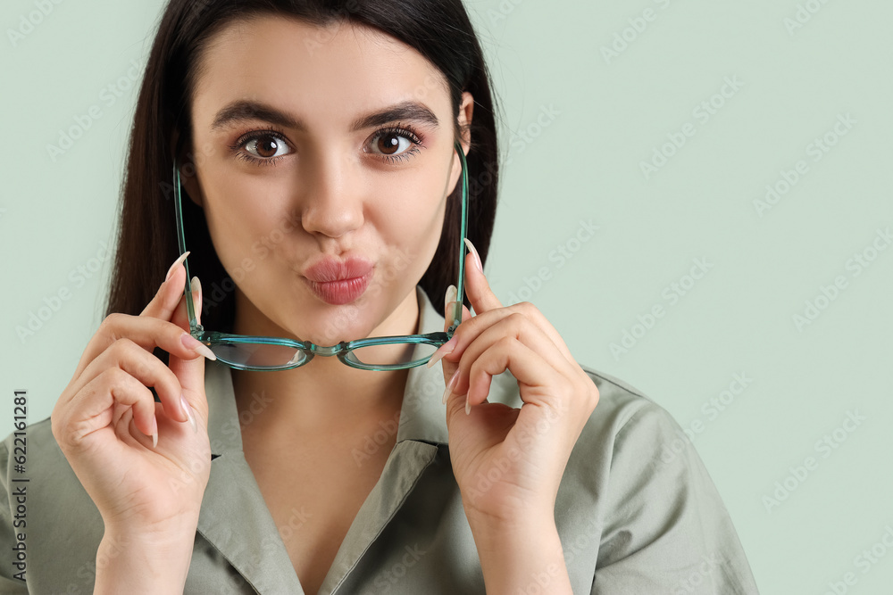 Cute young woman with glasses on  color background