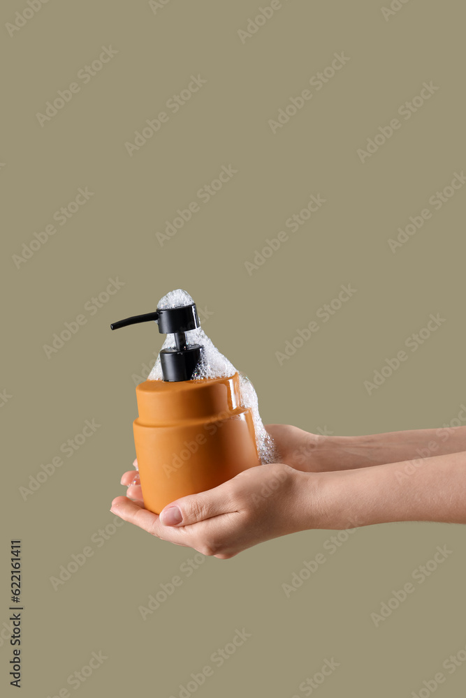 Hands with liquid soap on color background