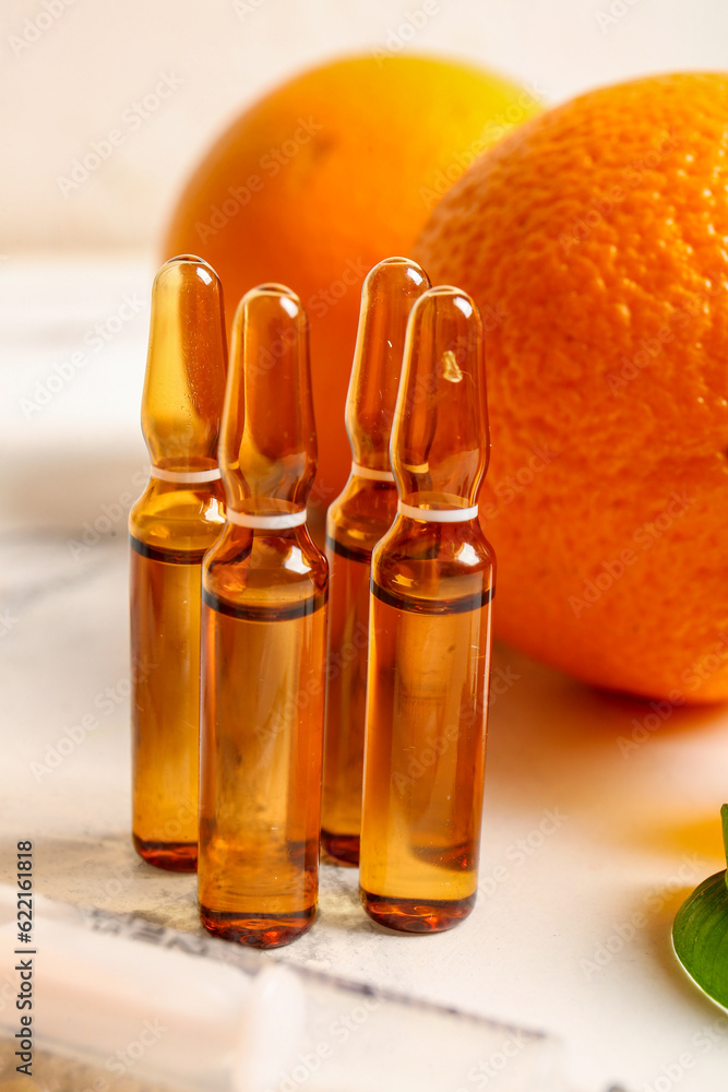 Ampoules with vitamin C and orange on white background