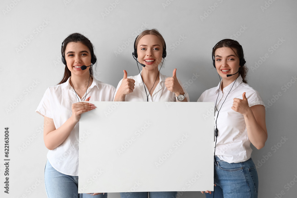 Female technical support agents with blank poster on light background