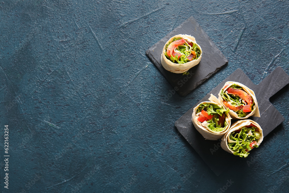 Boards of tasty lavash rolls with tomatoes and greens on black background