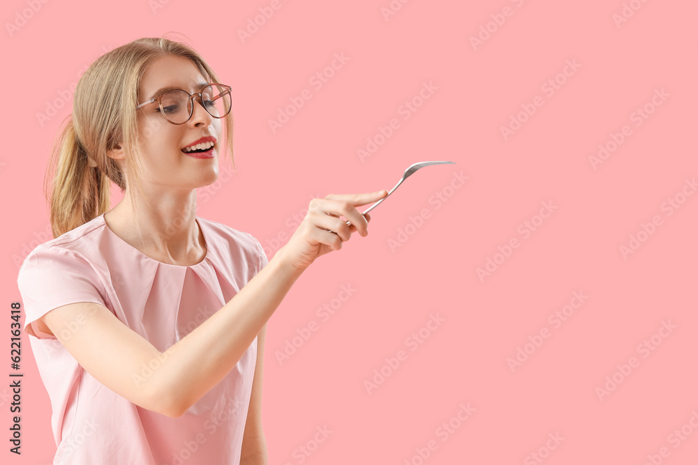 Young woman with fork on pink background