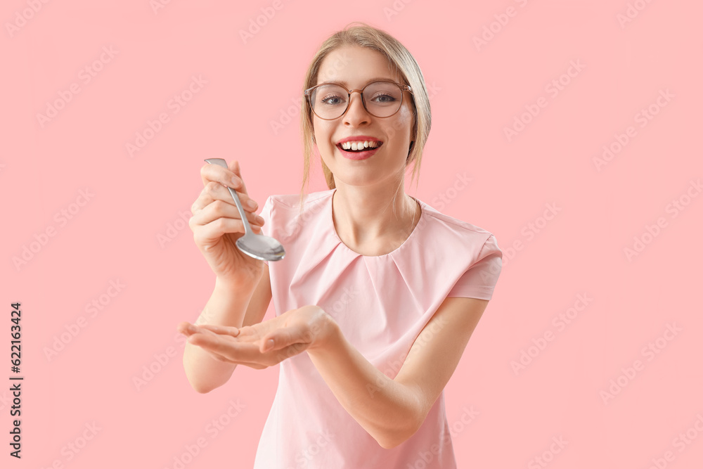 Young woman with spoon on pink background