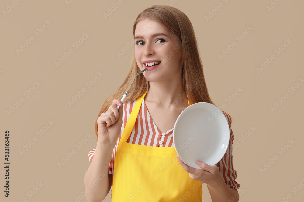 Young woman with fork and plate on beige background