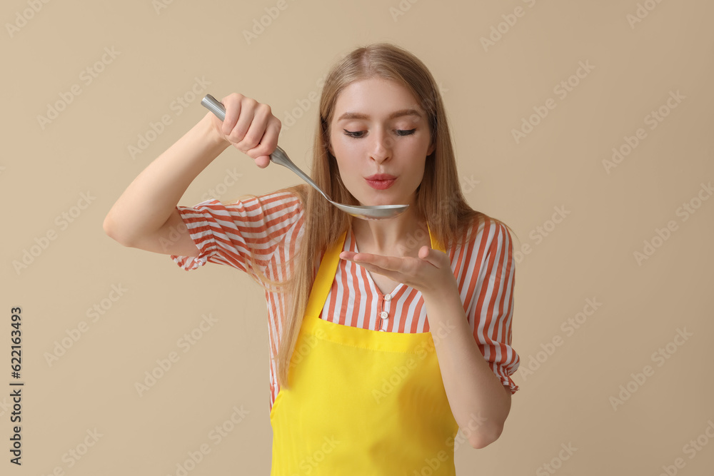 Young woman with ladle on beige background