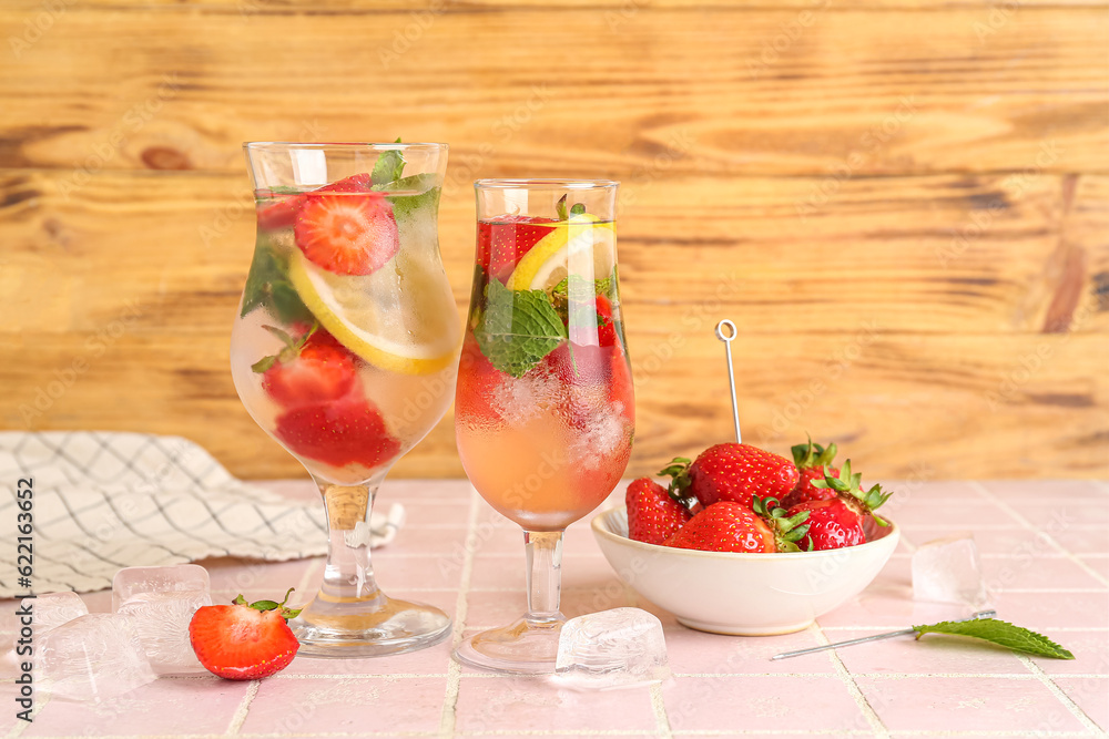 Glasses of fresh lemonade with strawberry and lemon on pink tile table