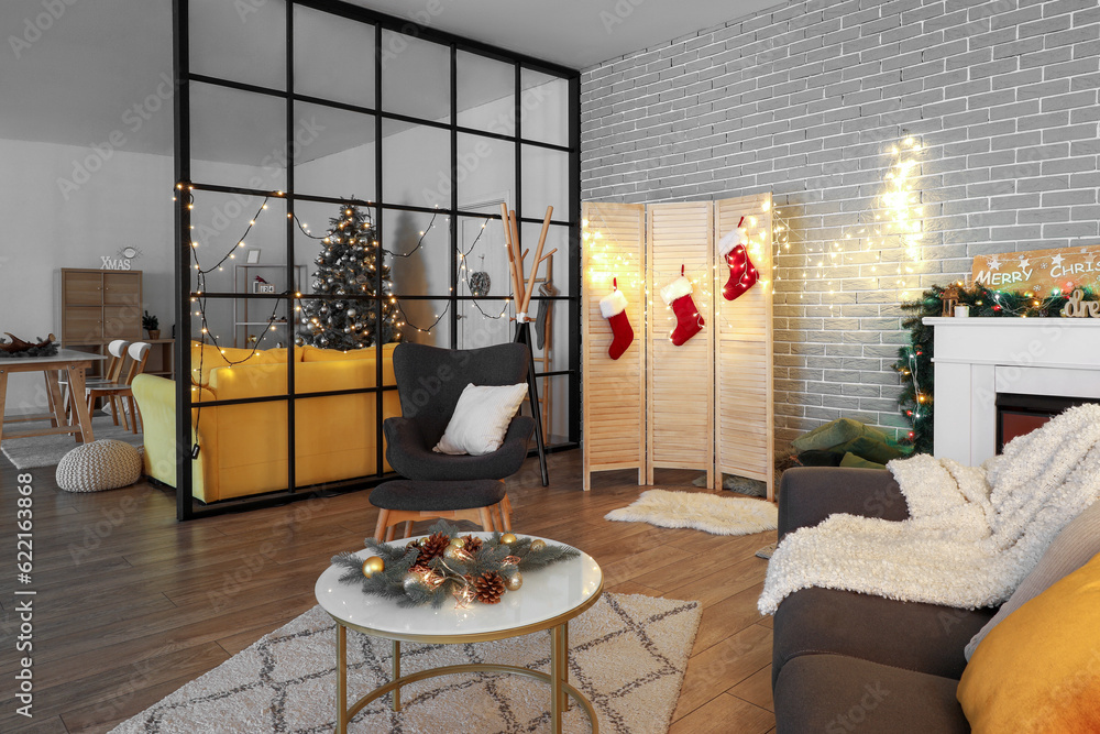 Interior of living room with Christmas decorations, sofa, armchair and fireplace